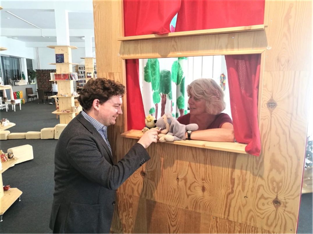 The chair of the Landshut Social Committee, Mayor Dr. Thomas Hasslinger, asks Ele Schöfthaler about the Home and Care project and the use of puppet theater and storytelling sessions in project work. (Source: Internet)