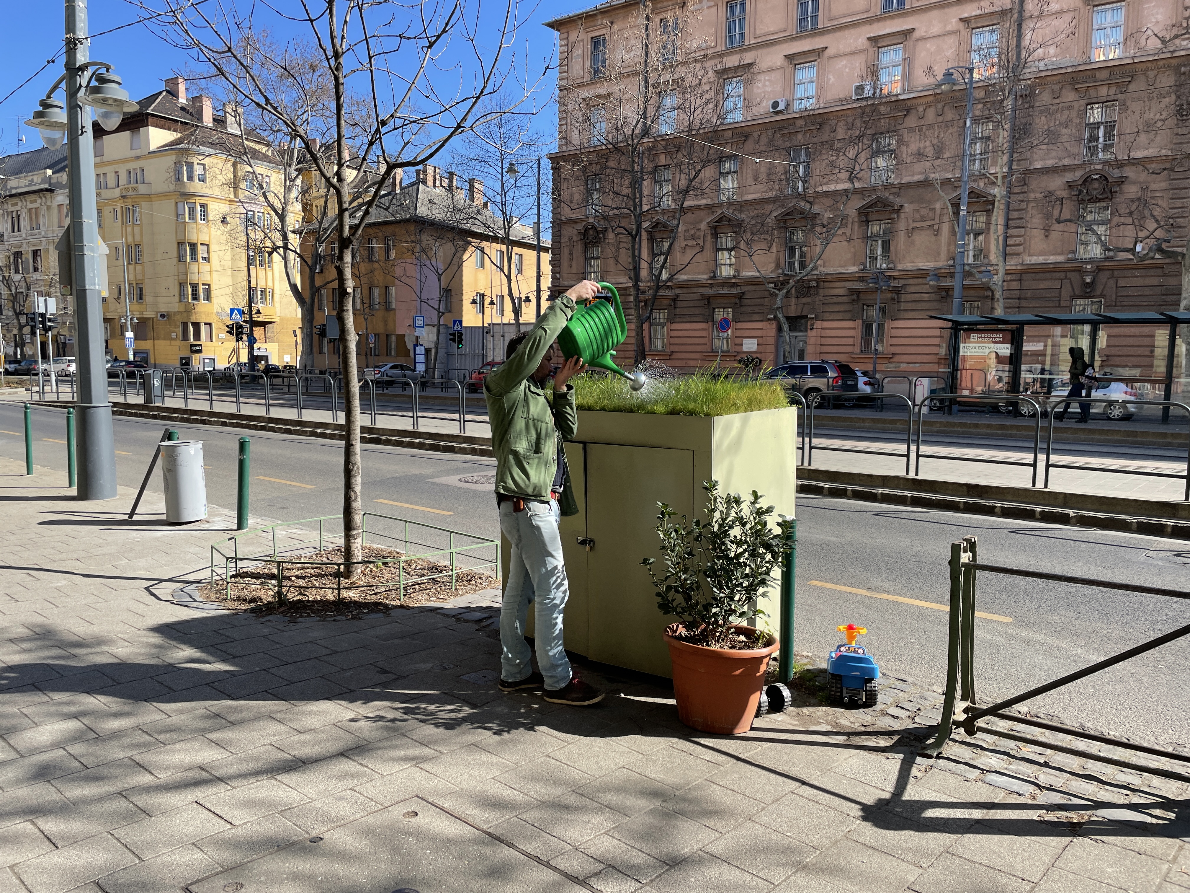 A bar owner waters a green spot. Photo by Levente Polyak